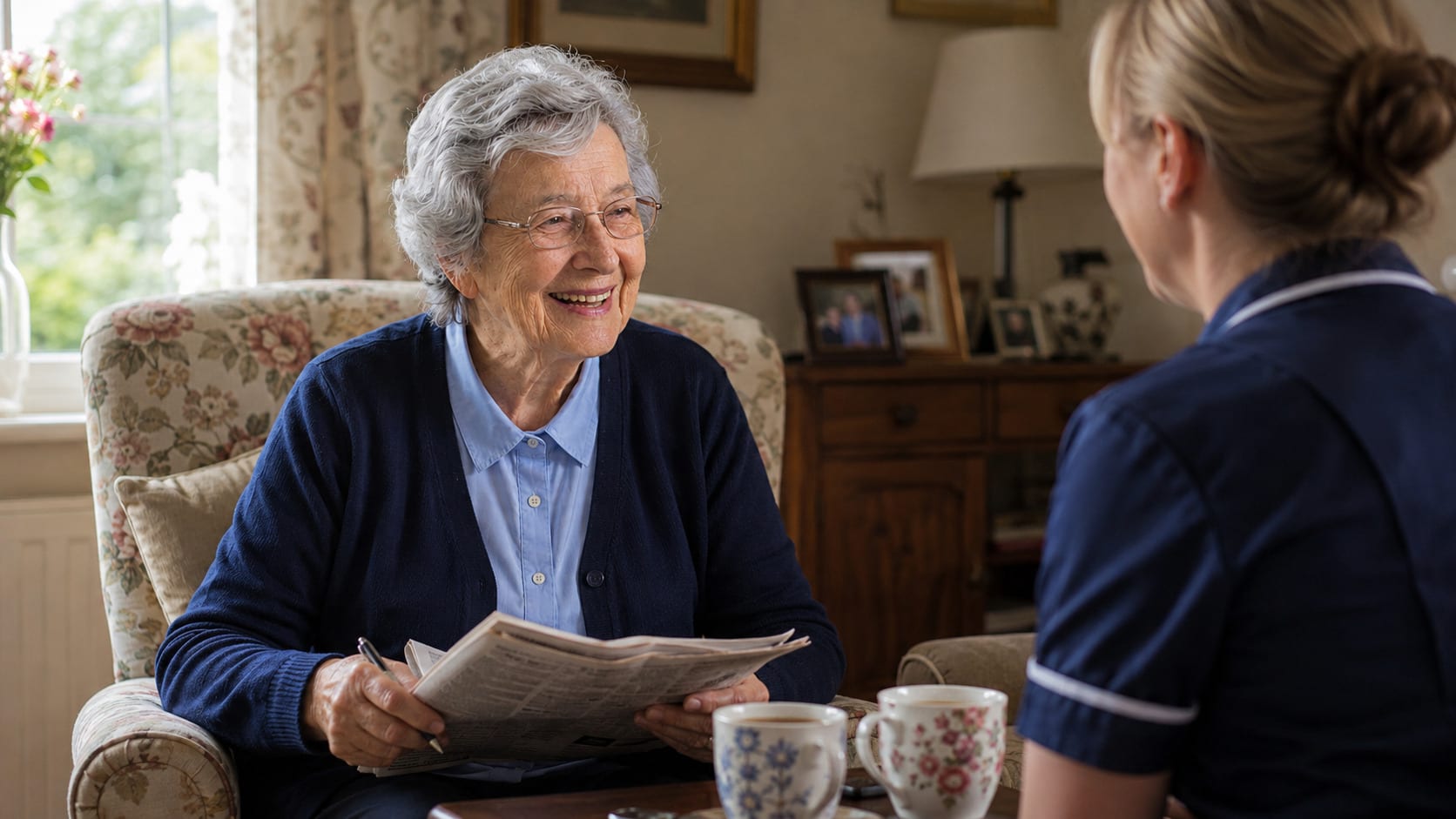 An older woman in an armchair looks up from a folded newspaper, pen in hand, mid-sentence.
